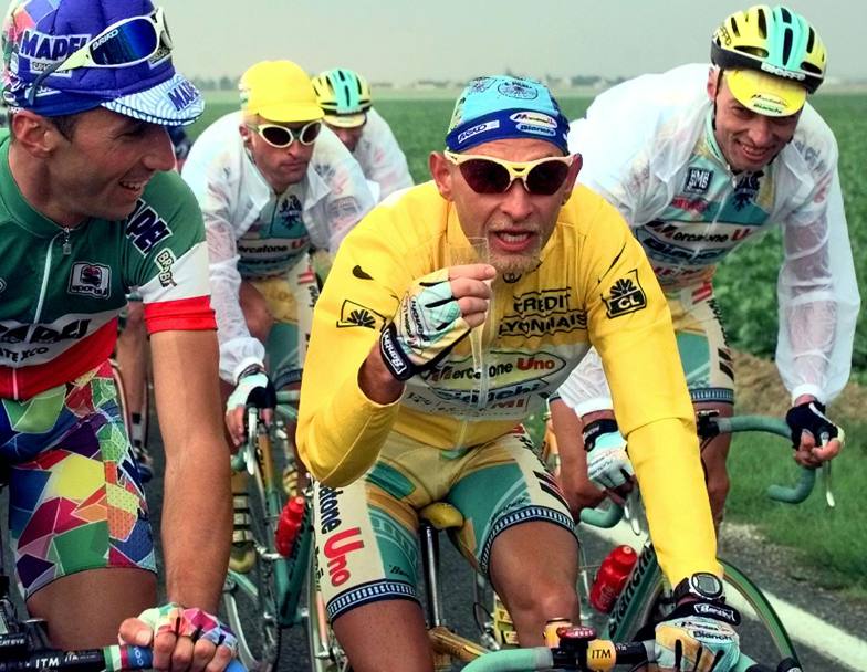 Tour de France 1998. 21 e ultima tappa, Marco Pantani festeggia con un bicchiere di champagne il suo trionfo. Lo affiancano sorridenti il campione italiano Andrea Tafi, e lo scalatore romagnolo Roberto Conti, suo compagno e corregionale. (Ap)